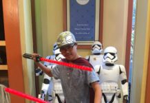 Tanner holding Star Wars swords at Disneyland store.