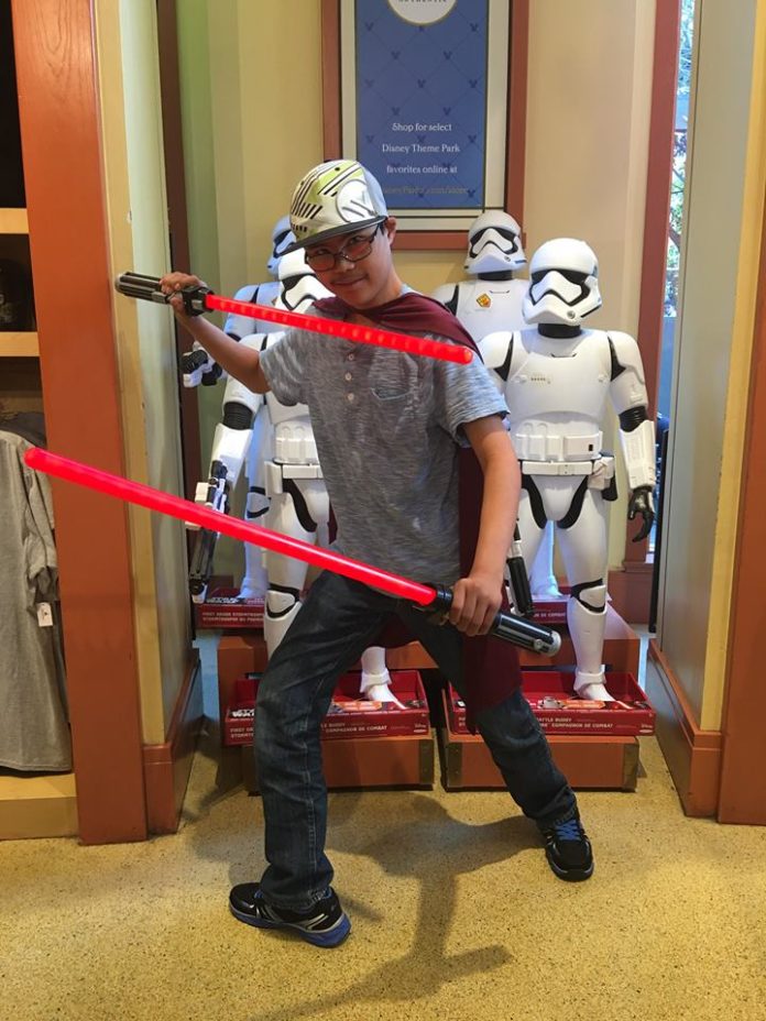 Tanner holding Star Wars swords at Disneyland store.